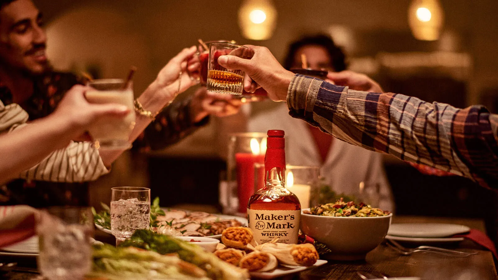 Friends cheering and enjoying Maker’s Mark bourbon at a dinner table 